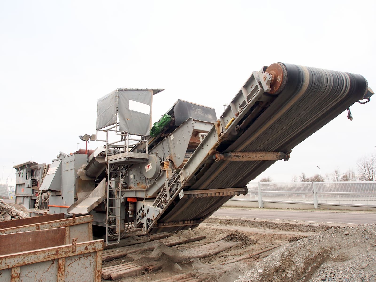 Mobile crusher discharging rock over its incline conveyor